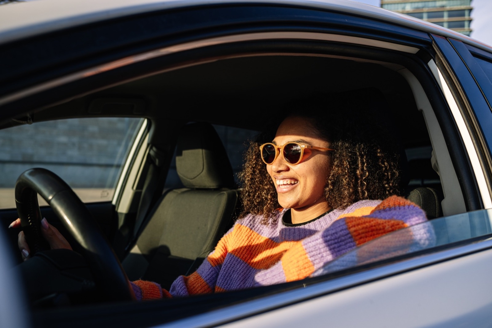 Smiling driver at the wheel after refinancing her auto loan for a lower monthly payment