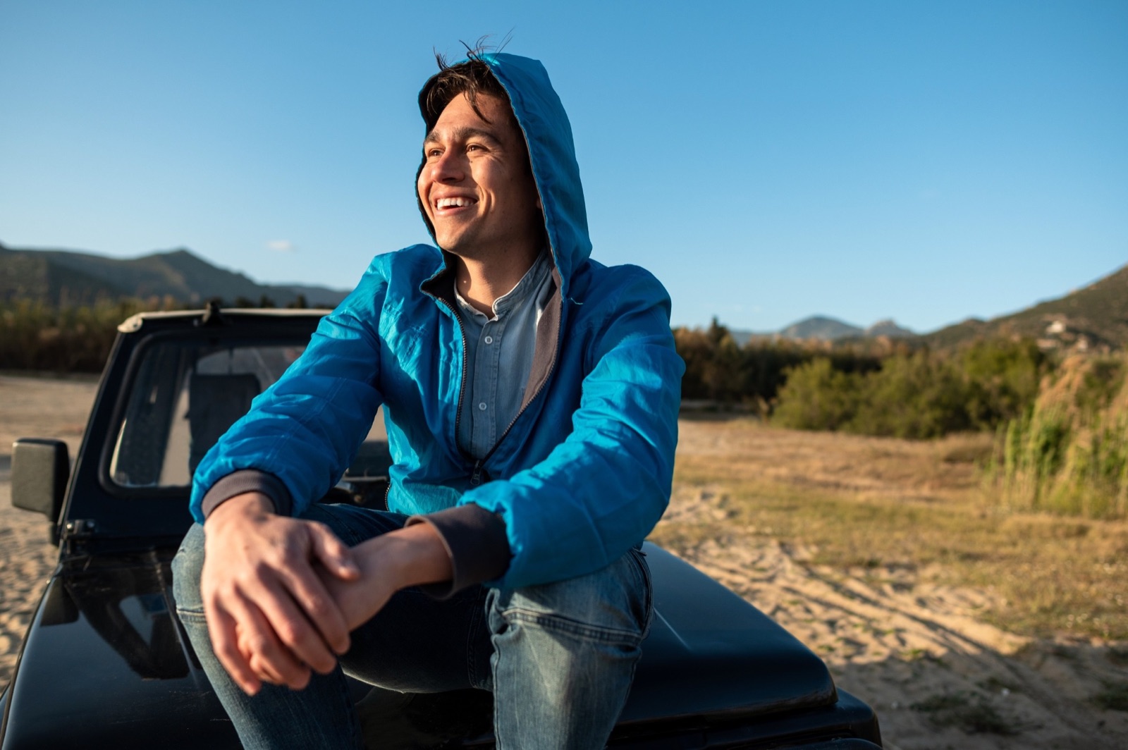 Man smiling beside his car after refinancing his auto loan