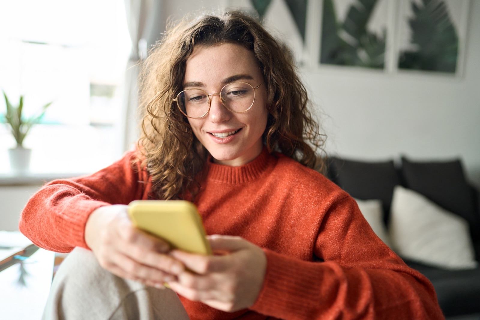 Woman checking her auto refinance rate on her phone at home