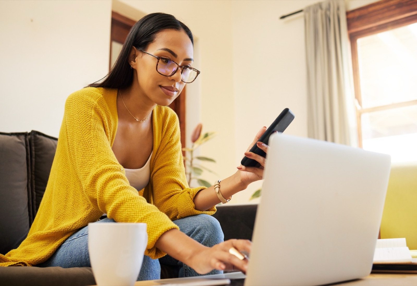 Woman at home comparing refinance offers on her phone and laptop