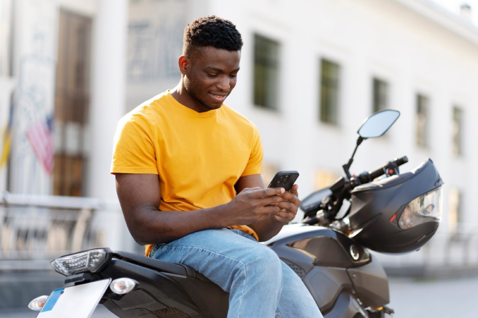Rider sitting on his motorcycle checking refinance offers on his phone